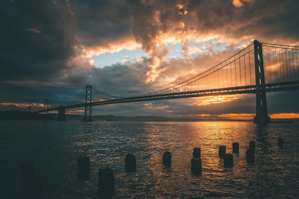Stunning sunset view of the Bay Bridge in San Francisco reflecting on water.